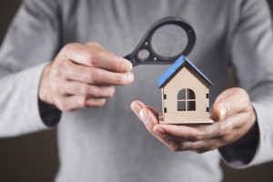 home search concept. Holds a magnifying glass and a house